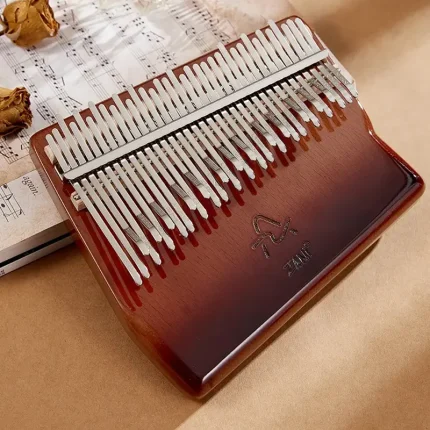 The Espresso Fade 34-key chromatic kalimba resting on sheet music next to dried roses, creating a vintage, artistic feel.