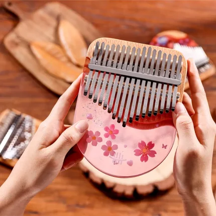 Hands playing Hluru 17 Key Solid Body Resin Kalimba in Sakura Pink with floral design