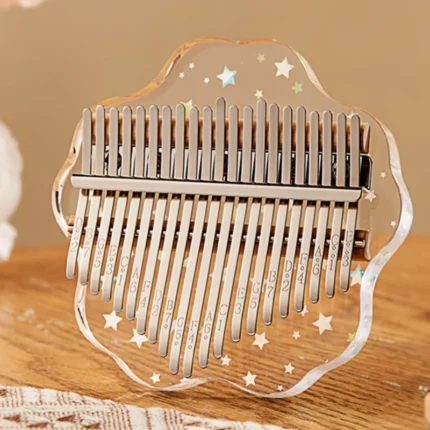A transparent acrylic 21-key kalimba with star patterns, displayed on a wooden table.