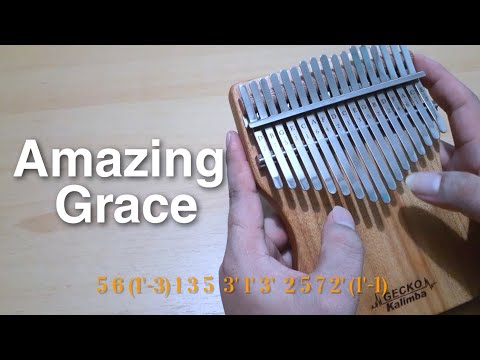 A person plays a wooden kalimba with metal tines. "Amazing Grace" (amazing-grace-kalimba-tabs-cover) is shown on the left, with numbered musical notes displayed at the bottom.